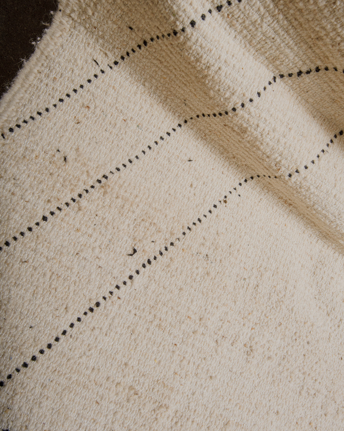 Back of wool beniourain showing irregular black wool strands.